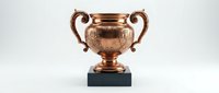 Elegant copper trophy cup with ornate handles on marble base isolated on white background for awards ceremonies and achievement recognition.