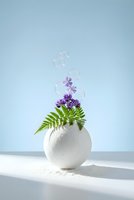 Minimalist white ceramic vase with purple lavender flowers and green fern leaves against soft blue background with floating soap bubbles for home decor.