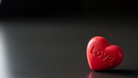 Red heart-shaped candy with love text on dark surface for Valentine's Day romance celebration and romantic holiday greeting cards.
