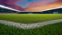 Empty soccer stadium at sunset with dramatic sky and illuminated floodlights casting glow over green grass field, view from corner marking line perspective.