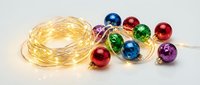 Colorful Christmas ornaments with warm LED string lights on white background, perfect for holiday decorating and festive seasonal design projects.