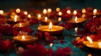 Glowing candles floating in water with red flower petals create romantic atmosphere. Soft focus candlelight reflection on dark turquoise surface for spa and meditation.