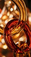 Intertwined glass tubes in warm amber and deep red tones with bokeh lighting, suitable for abstract backgrounds and design projects.