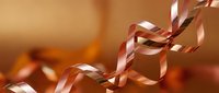 Elegant copper metallic ribbon curls flowing gracefully against warm golden background for luxury gift wrapping and festive holiday celebrations.
