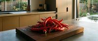 Fresh red chili peppers arranged on wooden cutting board in modern kitchen interior with natural lighting for culinary cooking and spicy food preparation.