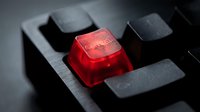 Red translucent keycap with circuit pattern on black mechanical keyboard, close-up macro shot for gaming and technology concepts.