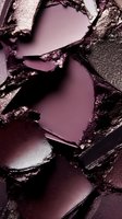 Crushed burgundy eyeshadow palette showing rich texture and metallic shimmer detail in macro photography, creating abstract patterns of broken cosmetic powder.