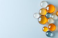 Colorful glass spheres in orange, blue, and clear tones arranged on light blue background with copy space for text.