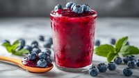 Fresh blueberry smoothie in glass with berries and mint leaves on wooden table. Healthy breakfast drink with antioxidants for wellness lifestyle.
