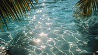 Sunlight creates mesmerizing patterns on turquoise water surface through palm leaves, reflecting tropical paradise atmosphere. Perfect for travel and wellness designs.