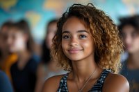 Young mixed-race woman with curly hair smiling confidently in modern office environment with diverse team colleagues in background for business concepts.