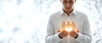 Young professional businessman holding glowing golden city skyline in cupped hands representing urban development and real estate investment opportunities.