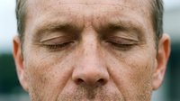 Middle-aged man with closed eyes and relaxed facial expression, displaying calm, peaceful demeanor. Suitable for wellness, meditation, mindfulness, stress relief, and mental health content.