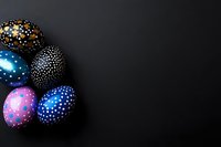 Colorful Easter eggs decorated with dots pattern on black background with copy space. Festive holiday composition for greeting cards and designs.