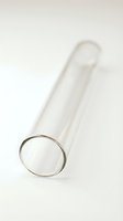 Empty glass test tube with metal rim and rounded bottom on white background, isolated laboratory equipment for scientific research and medical testing.