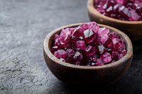 Pink crystallized sugar in wooden bowl on dark stone background, macro food photography for culinary and confectionery design projects.