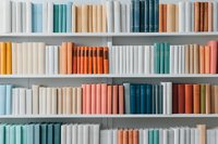 Colorful books arranged on white shelves in pastel and muted tones creating minimalist library aesthetic, modern bookshelf organization pattern.
