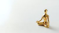 Golden metallic figure in lotus meditation pose on neutral background for wellness and mindfulness concepts.