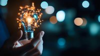 Hand holding glowing light bulb with sparkles and creative energy concept against blurred bokeh background. Innovation and inspiration concept for business solutions.