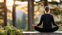 Young woman practicing yoga meditation in lotus pose outdoors at sunset with peaceful forest background for wellness and mindfulness lifestyle.