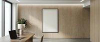 Modern minimalist office interior with blank white poster frame on wooden wall, natural lighting from large window, clean desk workspace for corporate branding mockup.