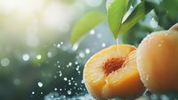 Fresh ripe peach cut in half with water drops and green leaves against blurred bokeh background, bright sunlight creates magical atmosphere.
