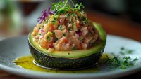 Fresh avocado half filled with colorful diced vegetables and herbs on elegant plate. Healthy appetizer perfect for restaurant menus and food blogs.