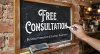 Hand writing free consultation offer on chalkboard sign for business promotion and marketing strategy services in professional office setting.