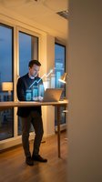 Young businessman analyzing financial growth data with holographic charts in modern office during evening hours for business planning and forecasting.