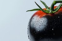 Fresh tomato with water droplets, dramatic dark and red contrast, green stem, light background, close-up macro shot for food and agriculture concepts.