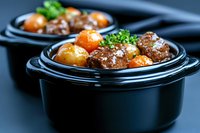 Tender beef meatballs with carrots and potatoes in rich gravy sauce, garnished with fresh parsley, served in black ceramic bowl for restaurant menu.