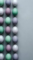 Colorful pastel Easter eggs arranged in rows on gray background with copy space for spring holiday celebration and festive decoration projects.