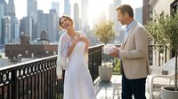 Young Caucasian couple celebrating engagement on urban rooftop terrace with city skyline backdrop during golden hour sunset for romantic lifestyle content.