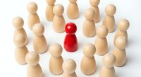 Red wooden pawn standing out among natural wood pawns on white background. Leadership, uniqueness, teamwork and business strategy concept.