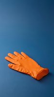 Bright orange rubber cleaning glove isolated on deep blue background, ready for design projects, household cleaning services, and sanitation concepts.
