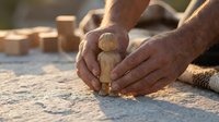 Hands protecting wooden pawn figure on concrete surface symbolizing care, protection, leadership and human resources management in business.