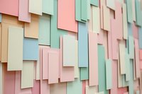 Abstract geometric wall with overlapping rectangular panels in pastel colors - pink, mint green, cream, and light blue creating dimensional architectural texture for modern interior design.