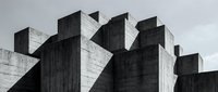 Brutalist concrete architecture with geometric angular forms and dramatic shadows against cloudy sky. Modern urban building design for architectural projects.