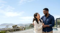 Young couple enjoying scenic coastal view from modern balcony, relaxed lifestyle moment for travel, real estate, and relationship content.