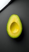 Halved avocado with pit removed on dark gray background, isolated for food photography, healthy eating, nutrition, and culinary design projects.