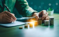 Business professional calculating home mortgage loan with coins and house icon hologram for real estate investment planning and financial analysis.