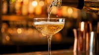 Pouring champagne into coupe glass with warm bokeh bar background, celebration and luxury beverage concept for events and hospitality.
