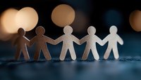 Paper cutout figures holding hands in row against blurred bokeh lights, symbolizing unity, teamwork and community support on dark background.