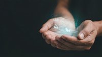 Hands holding glowing digital holographic sphere with futuristic interface elements and data visualization for technology and innovation concepts.