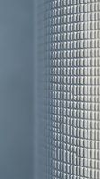 Modern curved skyscraper facade with repetitive window pattern against clear sky, suitable for corporate, architectural, and urban design projects.