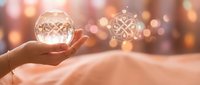 Hand holding glowing orb with geometric pattern against warm bokeh background, representing innovation, technology, and future vision for business concepts.