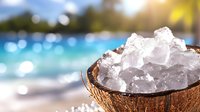 Fresh crushed ice in coconut shell half against blurred tropical beach background with sparkling bokeh lights and warm sunlight.