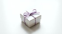 White gift box with purple ribbon bow isolated on white background for holiday celebrations and special occasions.