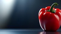 Fresh red bell pepper with green stem on dark background with dramatic lighting and copy space, macro food photography for healthy eating and cooking concepts.