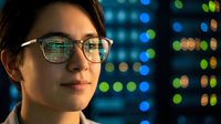Professional woman with glasses analyzing data on computer screen with colorful bokeh lights reflecting technology and digital innovation in modern workplace.